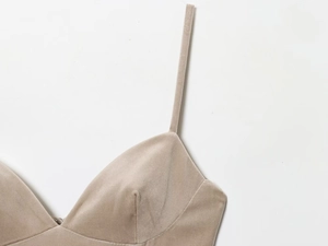 Détail de la robe en velours beige avec de fines bretelles et un corsage plissé