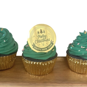 Macro shot of gold acrylic Merry Christmas cupcake toppers on green tree-shaped frosting
