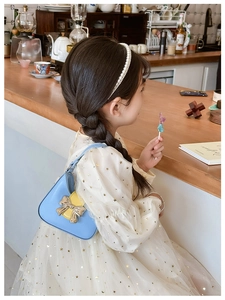 Detail of blue and yellow kids' crossbody bag with metal bow and star mesh dress