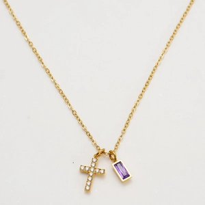 Macro view of gold cross pendant and purple birthstone on a delicate link chain