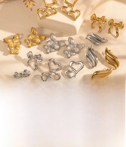 Detail of titanium steel earrings with heart and butterfly motifs in gold and silver