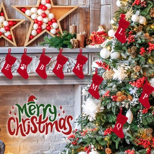 Detail of red knitted Christmas stockings with white letters and paw prints on a fireplace