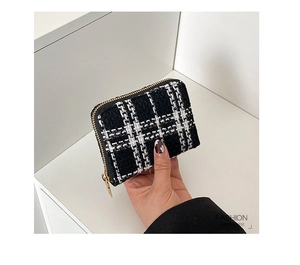 Close-up of black and white checkered tweed coin purse with gold zipper held by hand