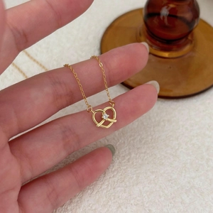 Macro shot of gold pretzel heart pendant with central zircon on delicate link chain