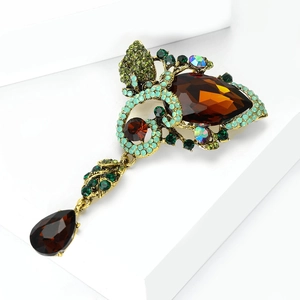 Macro shot of vintage bronze brooch featuring pear-shaped brown crystals and emerald gems