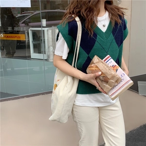 Gros plan sur un gilet en maille à losanges vert foncé vintage avec un col en V classique