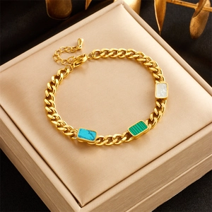 Dettaglio di bracciale a catena dorata con inserti blu, verdi e bianchi su portagioie