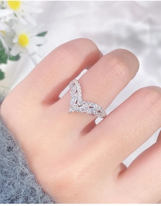Detail shot of a silver V-shaped chevron ring with fine sparkling diamonds worn on a finger