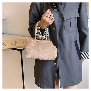 Detail of beige plush shell bag featuring pearl clasp closure and elegant pearl handle
