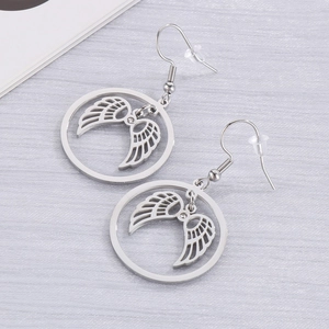Macro shot of silver stainless steel round hollow angel wing hook earrings on a grey surface
