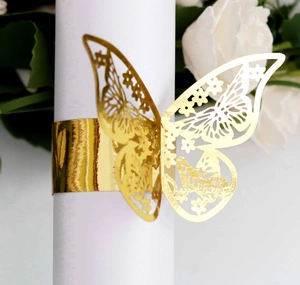 Close-up of golden hollow butterfly napkin ring with intricate floral laser-cut details