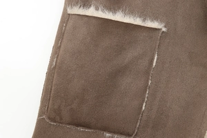 Detail of brown faux suede coat featuring plush cream fleece trim on the pocket seam
