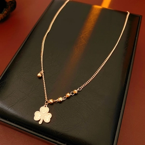 Close-up of golden clover heart pendant with 520 engraving on black leather surface