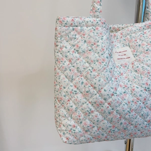 Détail du sac cabas matelassé avec motif floral rose et texture de couture en losange