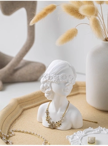 Detail of floral gold necklace and pearl strands on white plaster bust aesthetic display
