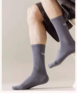 Gros plan sur des chaussettes grises côtelées avec lettrage blanc thu à la cheville