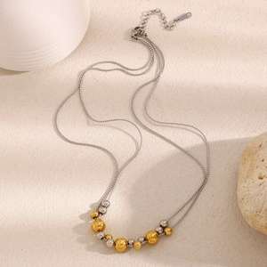Detail of double-layered silver chain necklace with mixed gold and silver beads on beige base