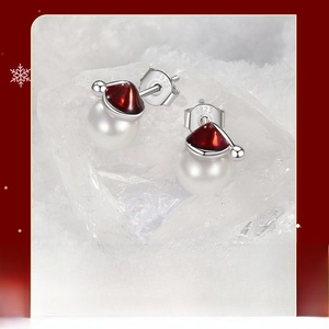 Macro shot of S925 silver Christmas hat pearl earrings on a winter ice background