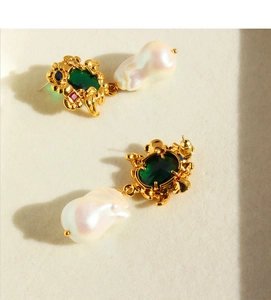 Macro detail of emerald gemstones and baroque pearls in vintage gold vine earrings