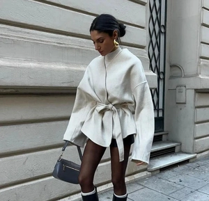 Photo de rue d'un manteau en laine gris clair avec ceinture et détails de sac à main