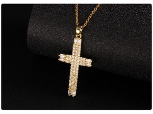 Detailed view of gold cross pendant with micro-paved zircons on black background