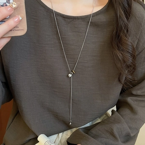 Elegant Y-shaped silver necklace with geometric pendants worn over dark clothing