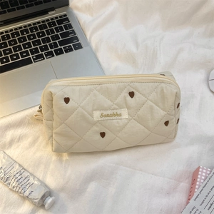 Detailed view of cream quilted makeup bag with brown heart embroidery and zipper