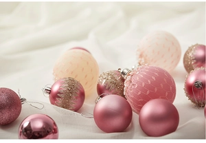 Nahaufnahme von rosa-goldenen Weihnachtskugeln mit Perlen auf weißem Stoff