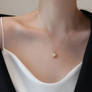 Minimalist gold heart shell pearl necklace worn by model on silk fabric backdrop