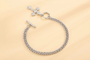 Detail of silver double-layer chain bracelet with rose embossed cross pendant and OT clasp