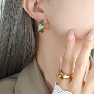 Geometric enamel earrings and lava textured gold ring shown on model for elegant style