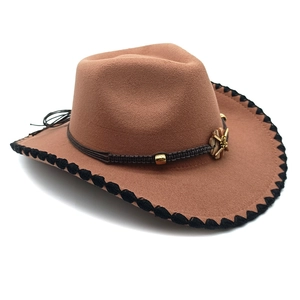 Detail of tan western cowboy hat featuring black stitching and braided star band