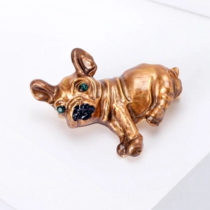 Detailed close-up of a bronze bulldog brooch with green rhinestone eyes on a white base