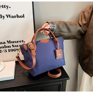 Detail of navy nylon tote bag with brown leather handles and adjustable shoulder strap