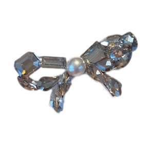 Elegant sparkling crystal bow hair clip with white pearl detail on white background