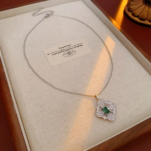 Detail of silver rhombus flower necklace with green gemstone in a wooden box