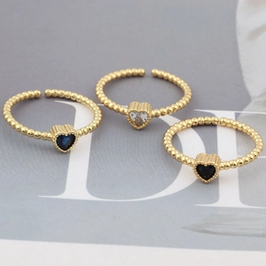 Detailed view of heart-shaped crystal rings in blue, clear, and black with gold beaded bands