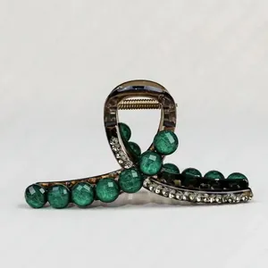 Detail of vintage emerald green beads and sparkling rhinestones on an amber hair claw