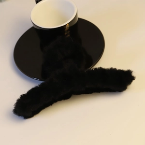 Nahaufnahme einer schwarzen Plüsch-Haarklammer auf minimalistischem weißem Hintergrund