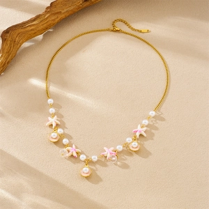 Gold necklace with pink starfish, shell and pearl pendants on a textured surface