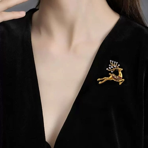 Exquisite gold reindeer brooch with red enamel and white crystals on a black velvet dress