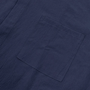 Macro shot of dark blue cotton linen fabric showing stitching detail on shirt pocket