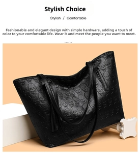 Detail of black leather tote bag featuring skull embossed pattern and tassel charms