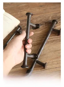 Detail of vintage cast iron door handles with grainy texture held by hand over rustic wood