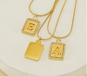 Détail des pendentifs lettres E et A en or avec zircons blancs sur socle en pierre