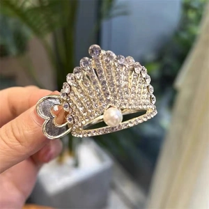 Macro view of gold crown hair clip with rhinestones and a large pearl detail