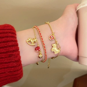Detailed view of red braided rope bracelet with gold rocking horse and heart charms