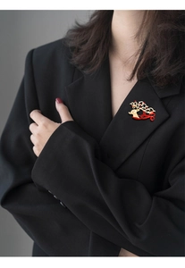 Detailed view of a gold and red reindeer brooch on a black blazer lapel for Christmas