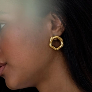 Chic irregular hexagonal gold hoop earrings with hammered lava texture on a female model