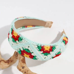 Detailed close-up of handmade knit floral headband on a rustic wood display